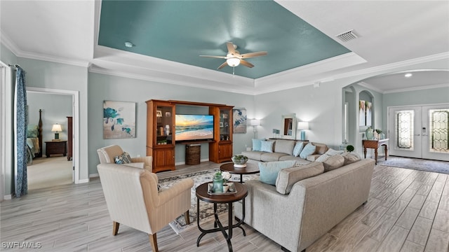 carpeted living room with a tray ceiling, ornamental molding, and ceiling fan