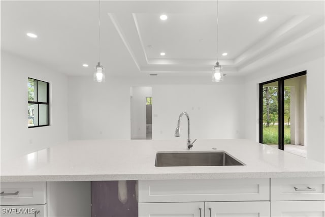 kitchen featuring a raised ceiling, plenty of natural light, decorative light fixtures, and sink