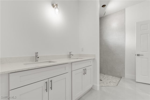 bathroom with tiled shower, vanity, and tile patterned flooring