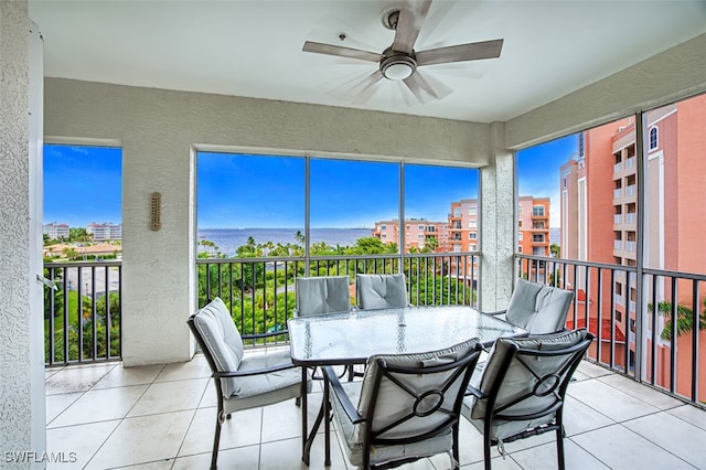 sunroom featuring ceiling fan and a water view