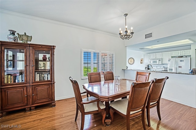 dining room with light hardwood / wood-style flooring, a chandelier, and ornamental molding