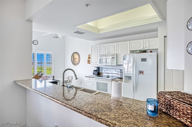 kitchen featuring a tray ceiling, white cabinets, white appliances, sink, and stone countertops