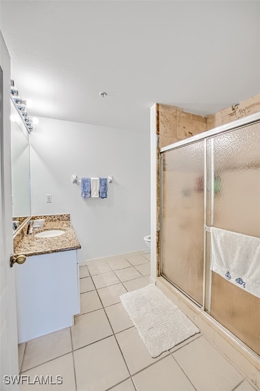 bathroom with vanity, a shower with shower door, tile patterned floors, and toilet