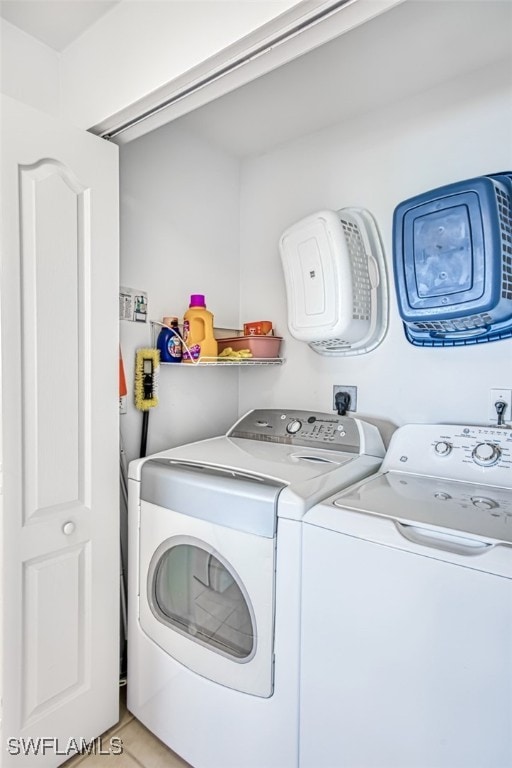 laundry room with light tile patterned flooring and washer and clothes dryer