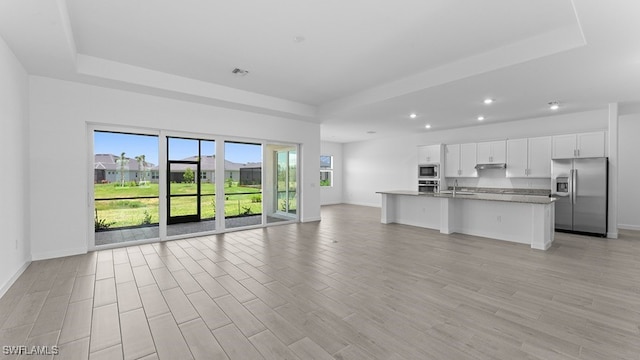 kitchen featuring stainless steel appliances, an island with sink, sink, light hardwood / wood-style flooring, and white cabinets