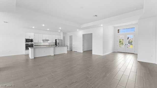 unfurnished living room with wood-type flooring, french doors, and sink