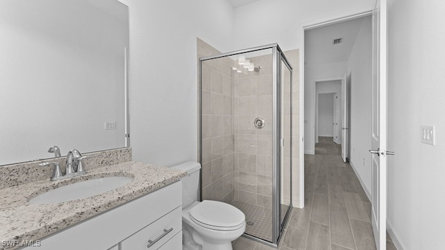 bathroom with vanity, a shower with door, toilet, and hardwood / wood-style flooring