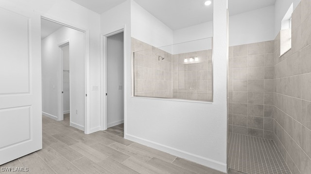 bathroom with wood-type flooring and a tile shower