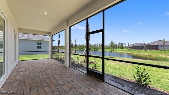 unfurnished sunroom featuring a water view