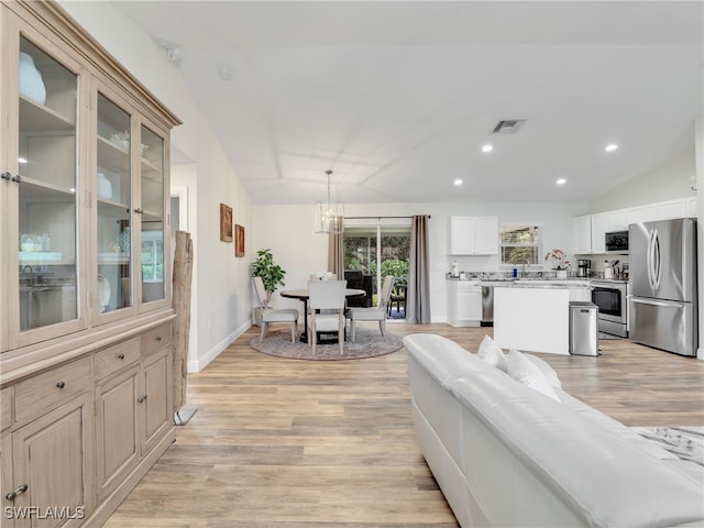 living room with lofted ceiling, a chandelier, and light hardwood / wood-style flooring