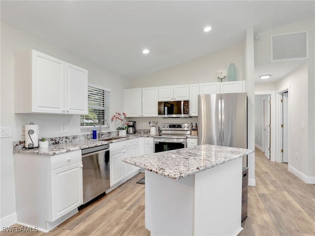 kitchen with sink, appliances with stainless steel finishes, vaulted ceiling, and light wood-type flooring