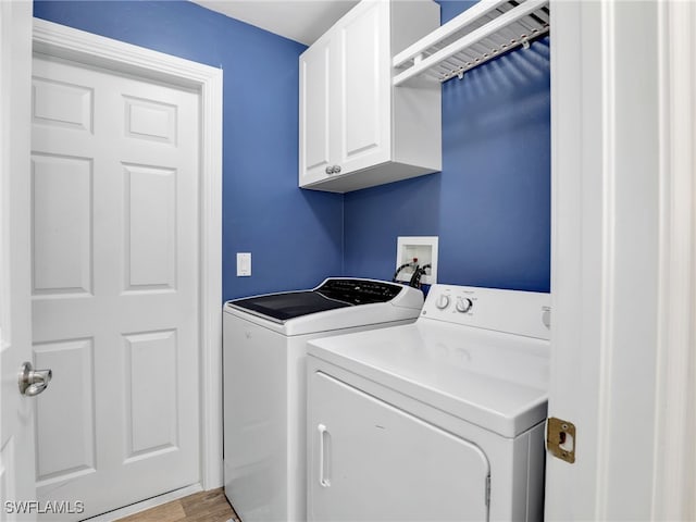 clothes washing area with cabinets, washing machine and clothes dryer, and light wood-type flooring