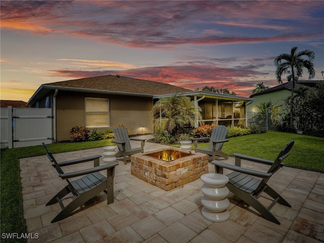 patio terrace at dusk featuring a yard and a fire pit