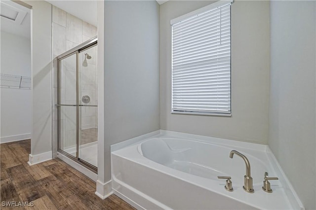 bathroom with hardwood / wood-style flooring, plus walk in shower, and a wealth of natural light