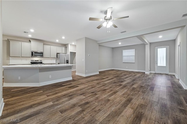 kitchen with dark wood-type flooring, gray cabinets, ceiling fan, stainless steel appliances, and decorative backsplash