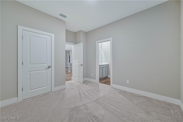 unfurnished bedroom featuring carpet and ensuite bath