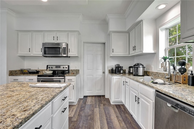 kitchen with crown molding, stainless steel appliances, white cabinetry, sink, and dark hardwood / wood-style floors