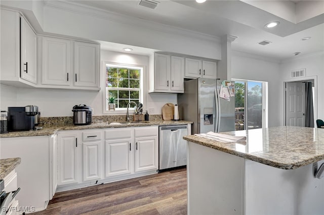 kitchen featuring a kitchen bar, appliances with stainless steel finishes, a wealth of natural light, and dark hardwood / wood-style floors