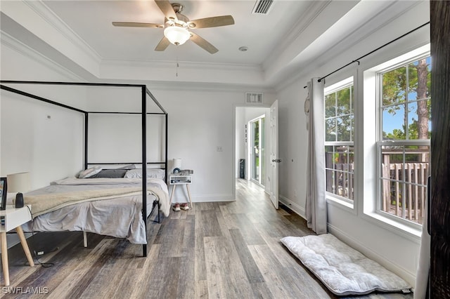 bedroom featuring hardwood / wood-style flooring, a raised ceiling, ceiling fan, and multiple windows