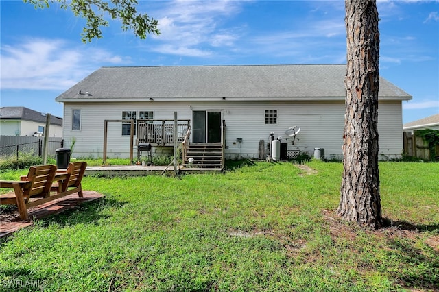 back of house featuring a lawn and a deck