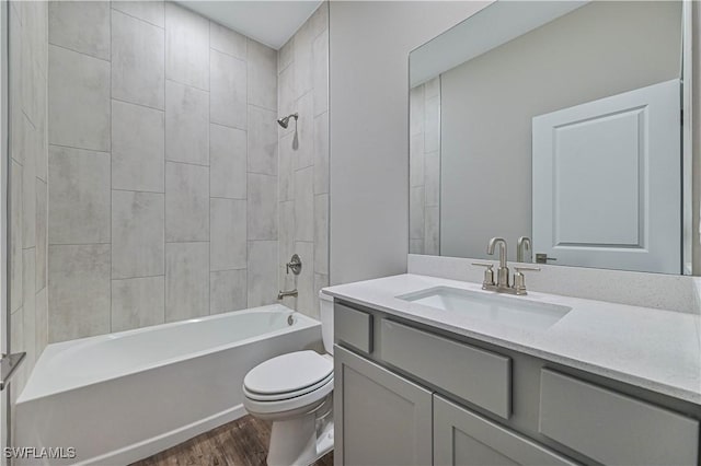 full bathroom with tiled shower / bath combo, vanity, hardwood / wood-style floors, and toilet