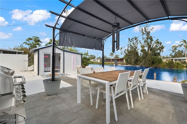 view of patio featuring a water view and an outbuilding