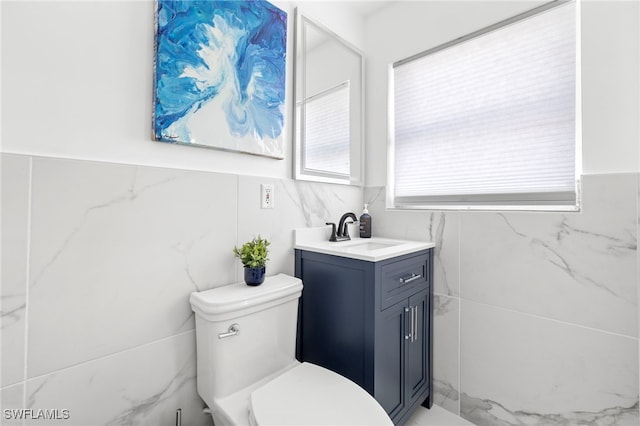 bathroom featuring vanity, toilet, and tile walls