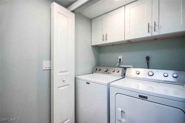 laundry room featuring washing machine and clothes dryer and cabinets