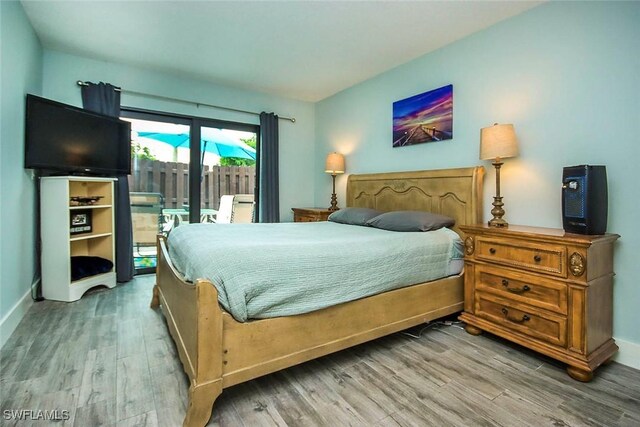 bedroom with access to outside and hardwood / wood-style floors