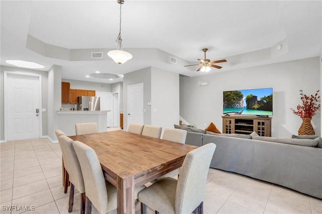 dining room with light tile patterned flooring, a raised ceiling, and ceiling fan