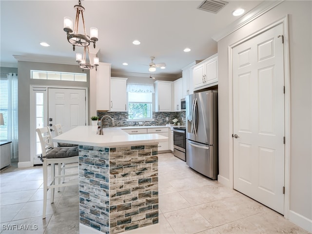 kitchen with pendant lighting, ceiling fan with notable chandelier, light tile patterned floors, a breakfast bar, and appliances with stainless steel finishes