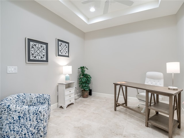 home office featuring a tray ceiling and ceiling fan