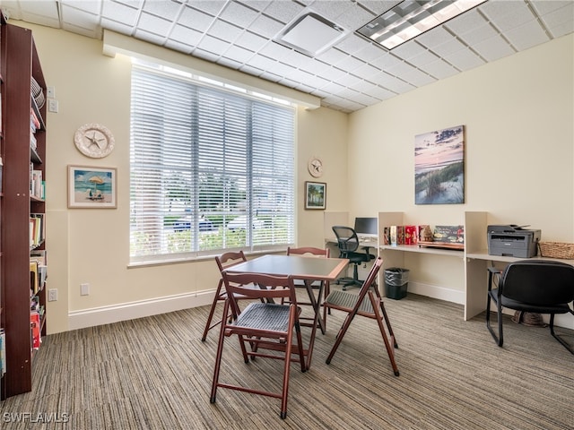 carpeted dining area featuring a paneled ceiling