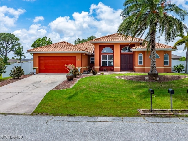 mediterranean / spanish home featuring stucco siding, concrete driveway, an attached garage, a front yard, and fence