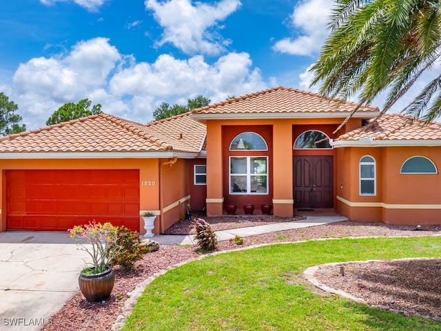 mediterranean / spanish home with concrete driveway, a tile roof, an attached garage, and stucco siding