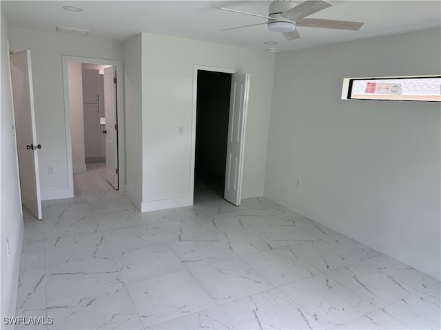 unfurnished bedroom featuring a closet, tile patterned floors, ceiling fan, and a walk in closet