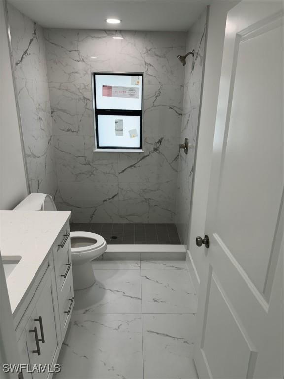 bathroom with vanity, toilet, tile patterned floors, and a tile shower