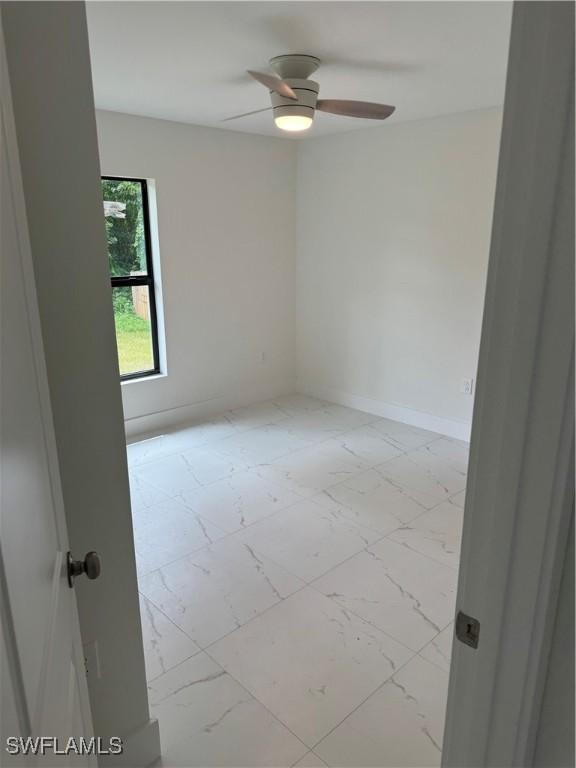 tiled spare room featuring ceiling fan