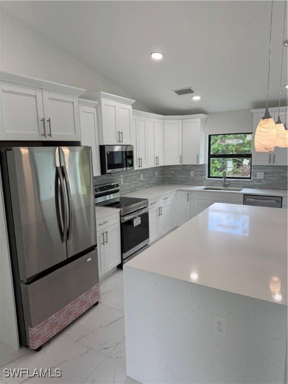 kitchen with appliances with stainless steel finishes, white cabinets, light tile patterned floors, and backsplash