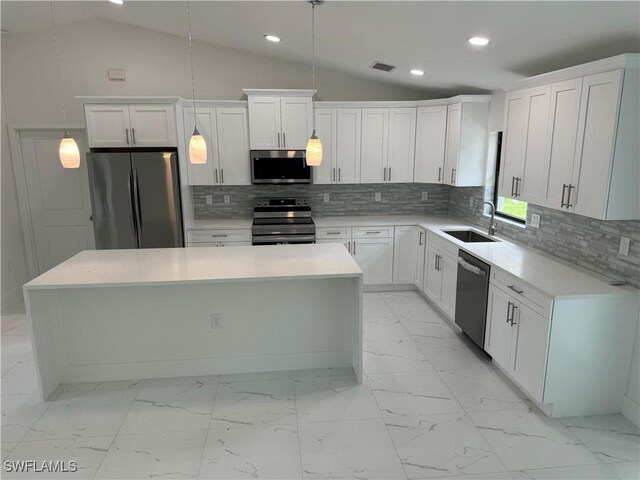 kitchen with decorative light fixtures, a center island, decorative backsplash, and stainless steel appliances