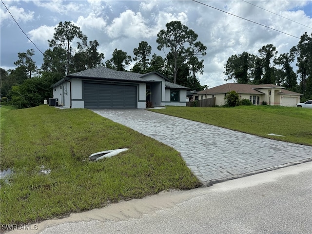 single story home featuring central air condition unit, a garage, and a front lawn