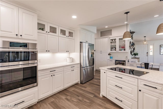 kitchen featuring stainless steel appliances, white cabinetry, hanging light fixtures, and hardwood / wood-style flooring