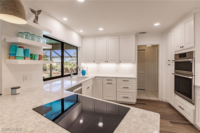 kitchen with double wall oven, dark hardwood / wood-style floors, white cabinetry, and sink