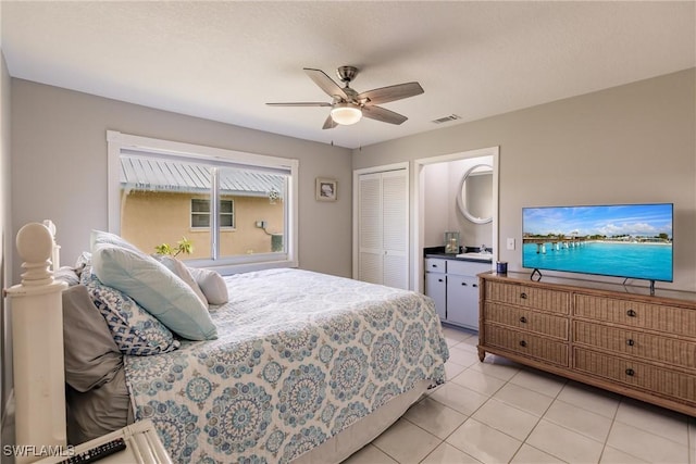 tiled bedroom with ensuite bath, a closet, and ceiling fan