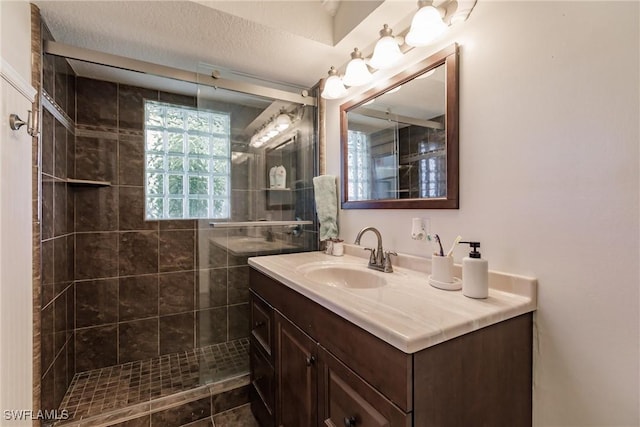 bathroom featuring vanity, a textured ceiling, and tiled shower