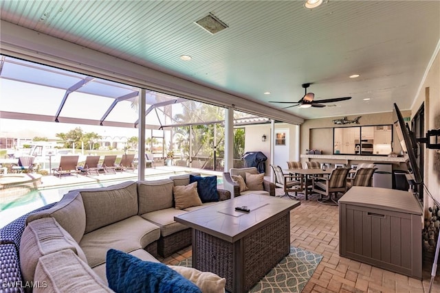 view of patio featuring ceiling fan, outdoor lounge area, and glass enclosure