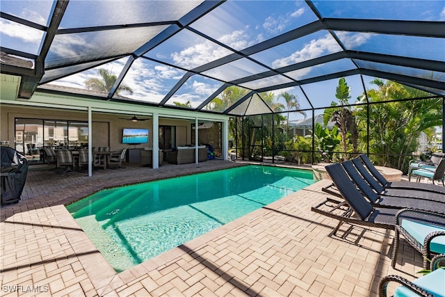 view of swimming pool with an outdoor living space, a patio, ceiling fan, and a lanai