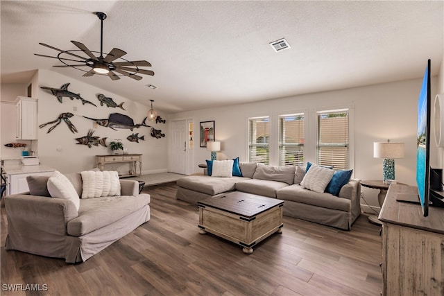 living room featuring wood-type flooring, vaulted ceiling, a textured ceiling, and ceiling fan