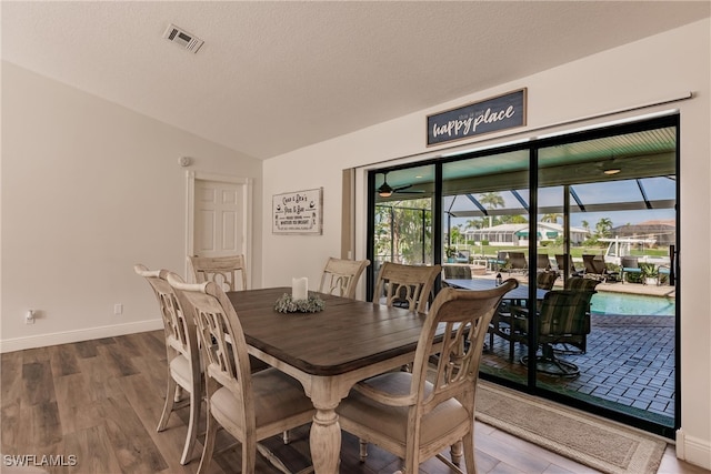 dining space featuring lofted ceiling, a textured ceiling, and wood-type flooring