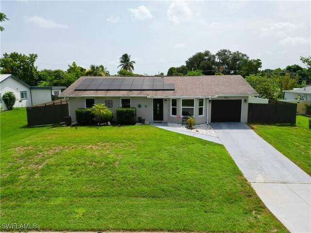 ranch-style home featuring a garage, a front lawn, and solar panels